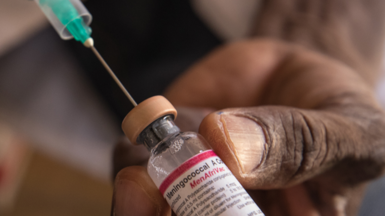 Syringe is inserted into a vial of the MenAfriVac vaccine.